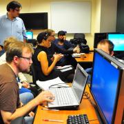 a group of people in front of computers working together at a hackathon